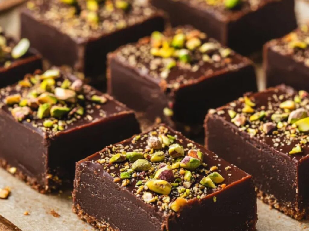 A beautifully arranged Dubai-Style Chocolate Pistachio Cake topped with crushed pistachios, set on a golden plate.