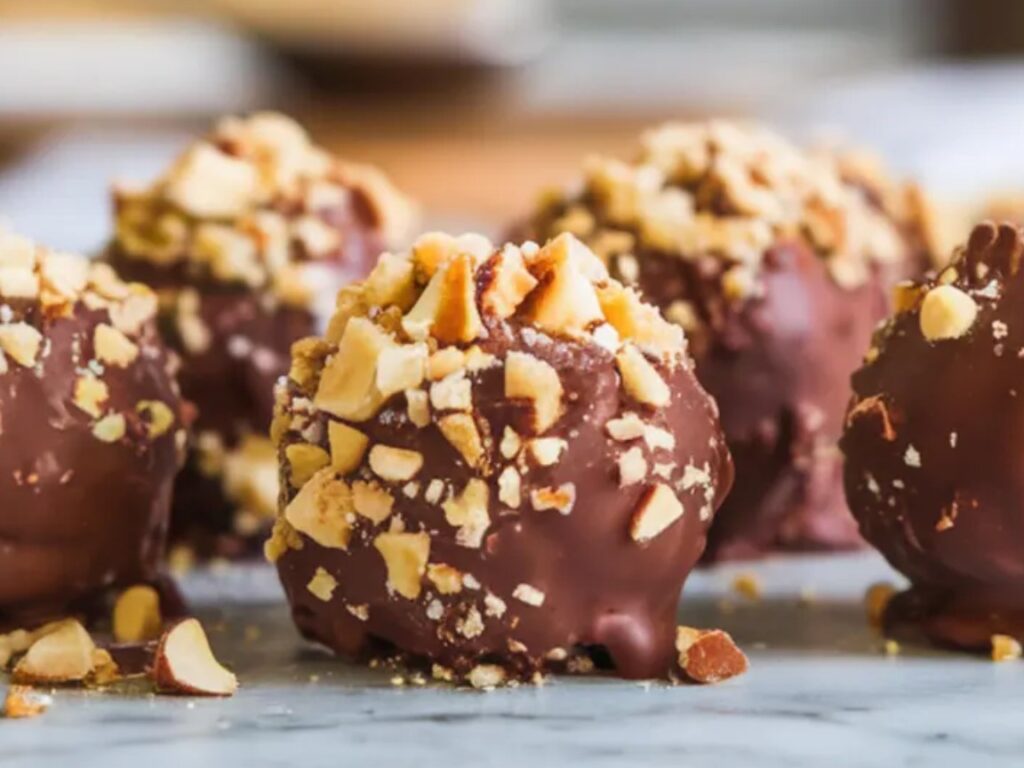 Bite-sized cheesecakes dipped in dark chocolate and topped with crushed nuts.